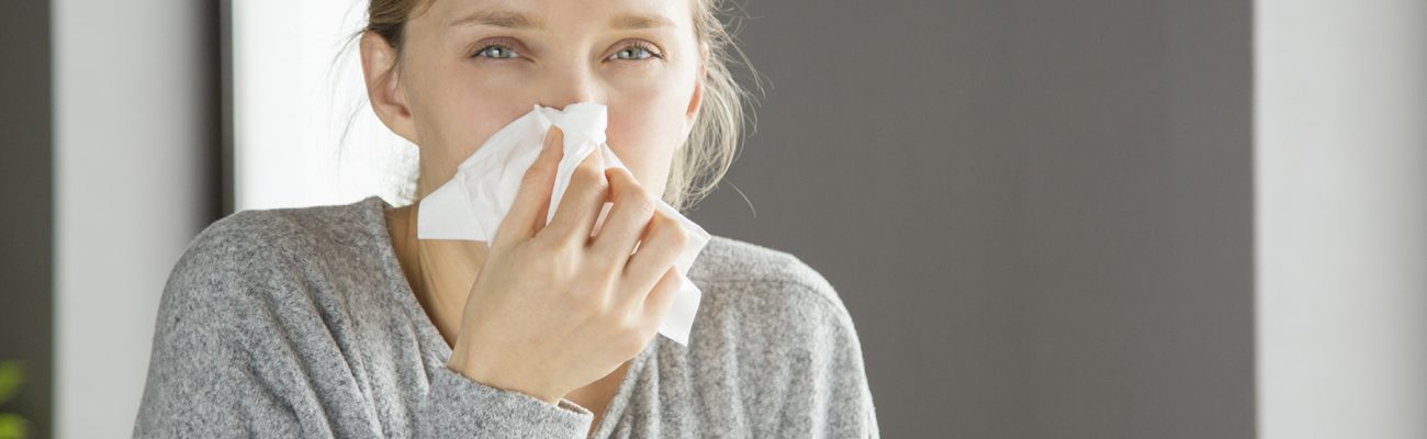 Pensive unhappy girl suffering from running nose. Young woman covering nose with tissue. Snuffle concept